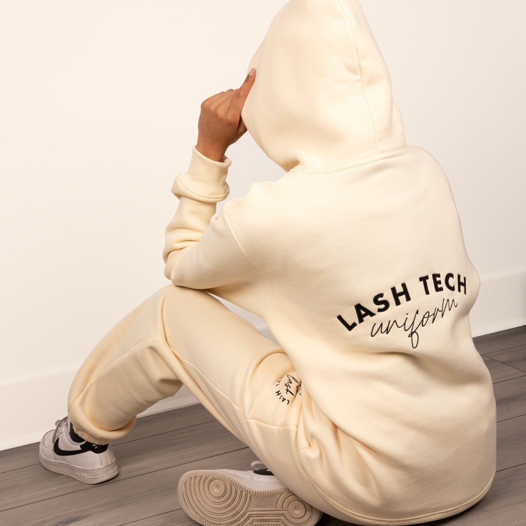 Model wearing a cream loungewear set with the hood up